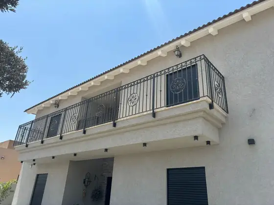 גדר ברזל מעוטרת עם פסגות מוזהבות לאורך חזית הבית